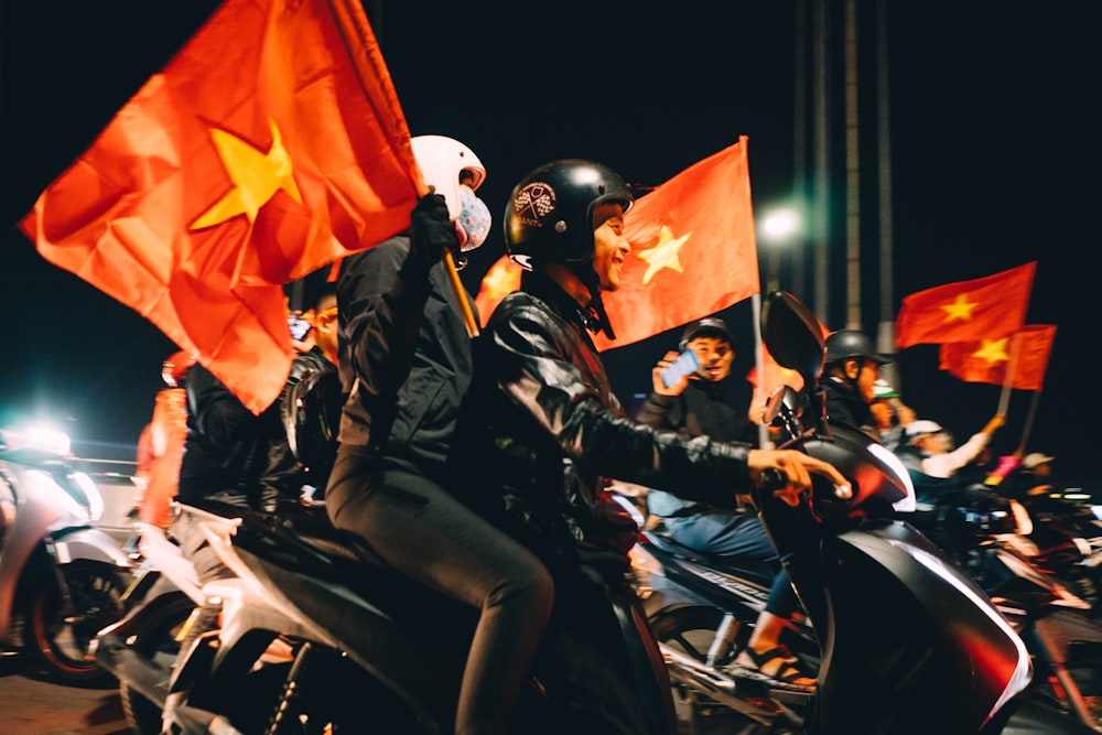 people riding motorcycles and holding flags during night
