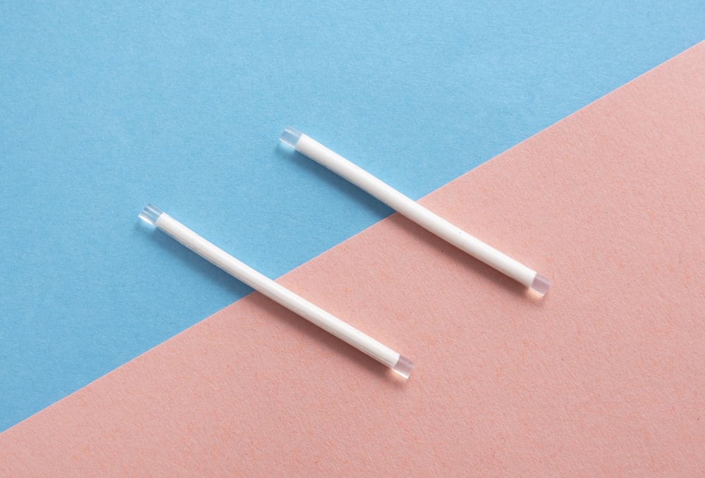 two white toothbrushes on a pink and blue background