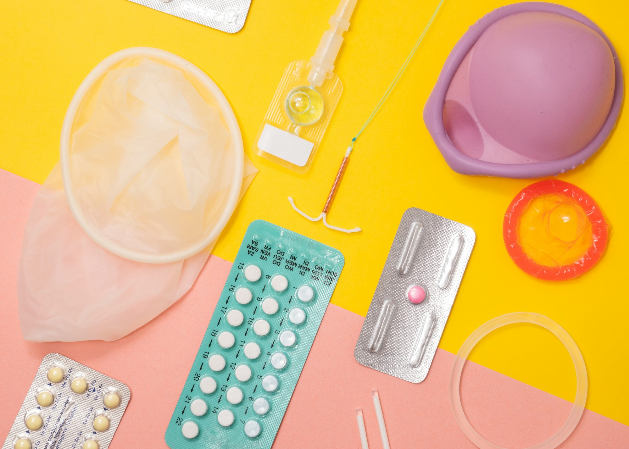 different types of contraception on a table such as oral contraceptive pills, condom, vaginal ring, IUD and more