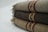 Three folded woolen blankets with fringe on the sides and decorative stripes in shades of brown and red.