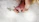A baby's hand gently holds small white flowers, while the feet rest on a soft, fluffy surface. Warm, glowing lights create a serene atmosphere around the baby, enhancing the delicate and tranquil scene.
