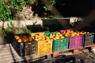 Crates of vibrant fresh fruit being loaded onto a delivery truck at a bustling warehouse.