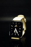 Modern minimalist watch with a black strap and gold details on a clean white background