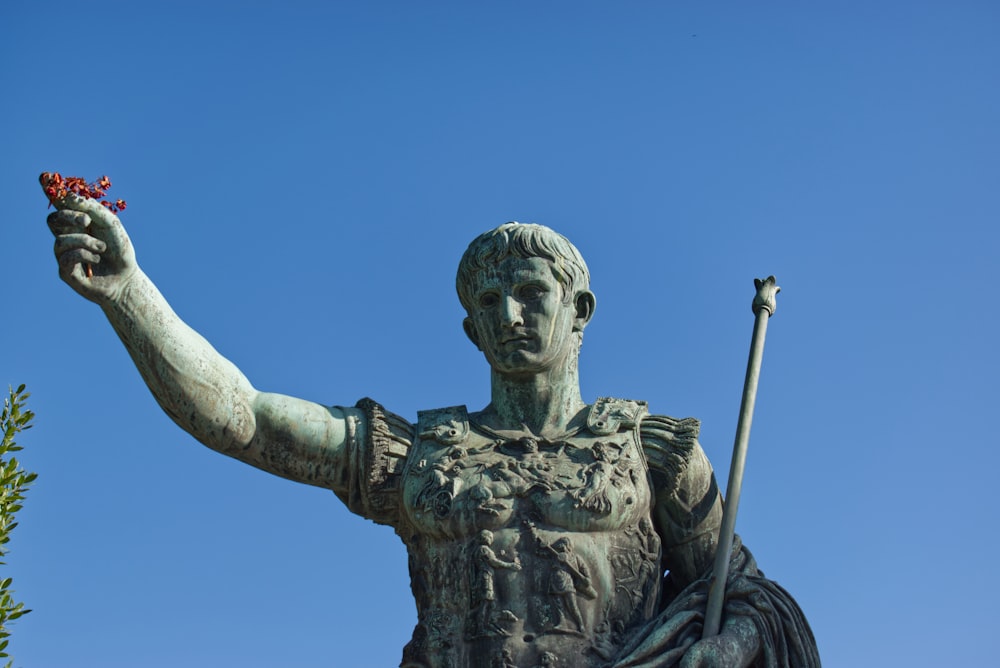 hombre sosteniendo la estatua del palo bajo el cielo azul durante el día