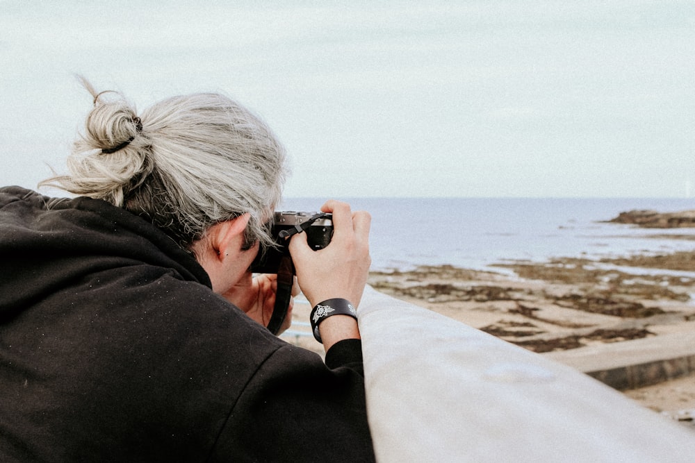 persona che scatta foto dell'oceano usando la macchina fotografica