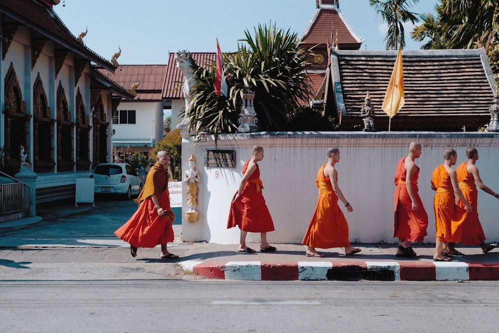 monks walking near wall beside street