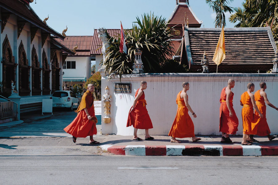 Monks in orange robes walking past a temple in Chiang Mai