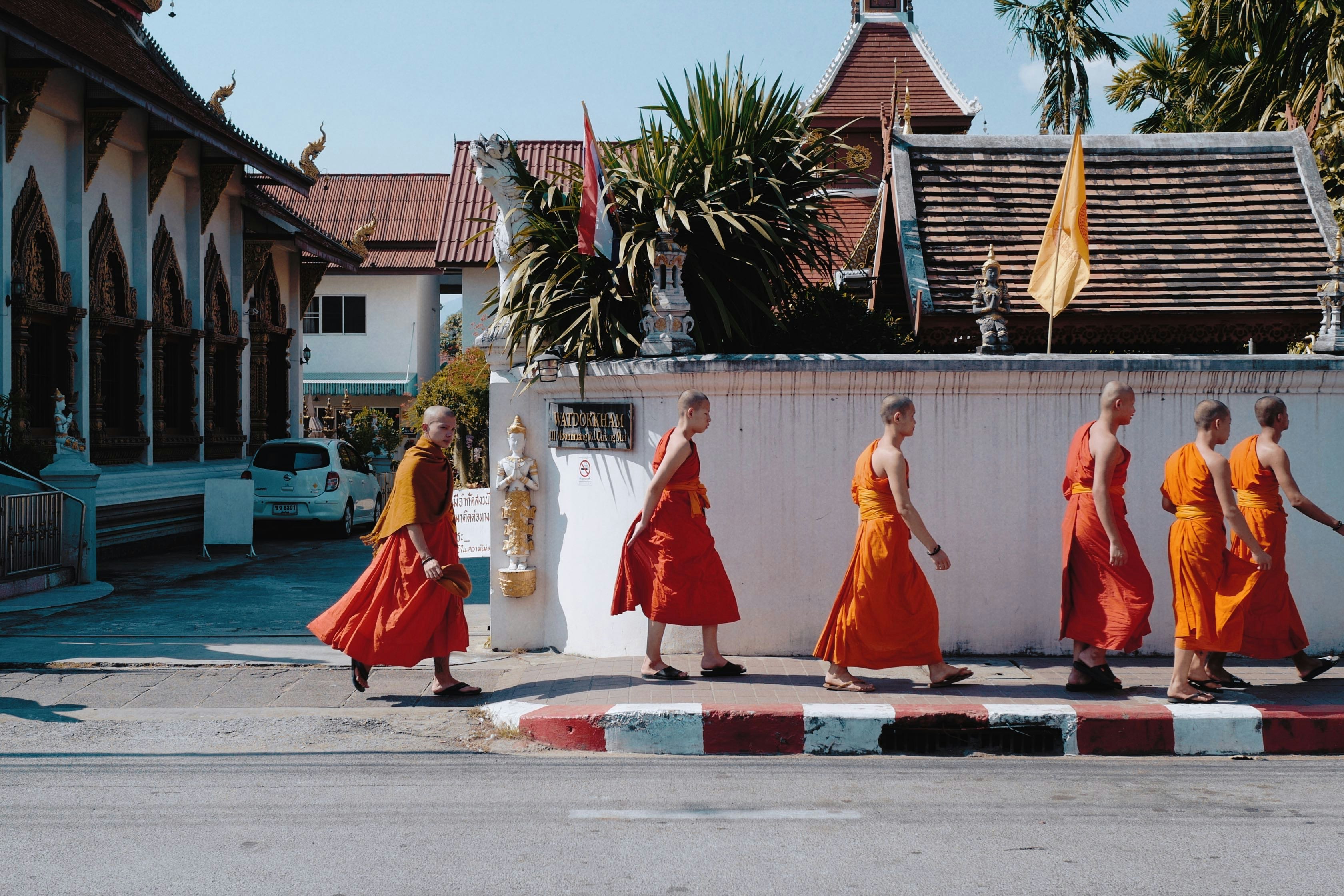 monks walking near wall beside street