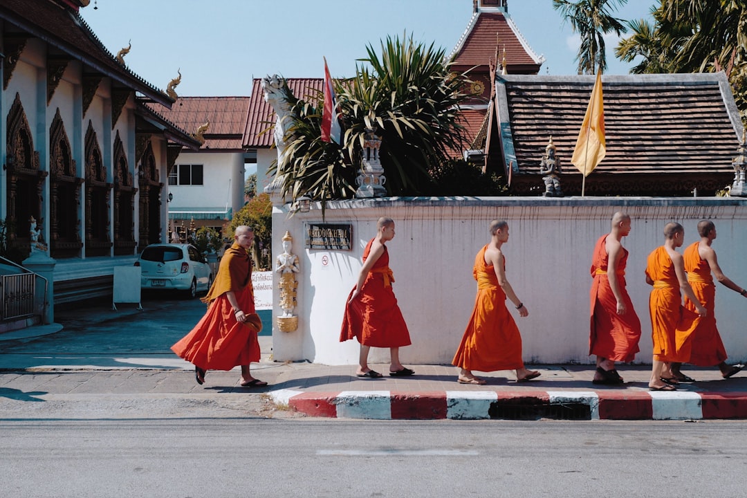 monks walking near wall beside street,