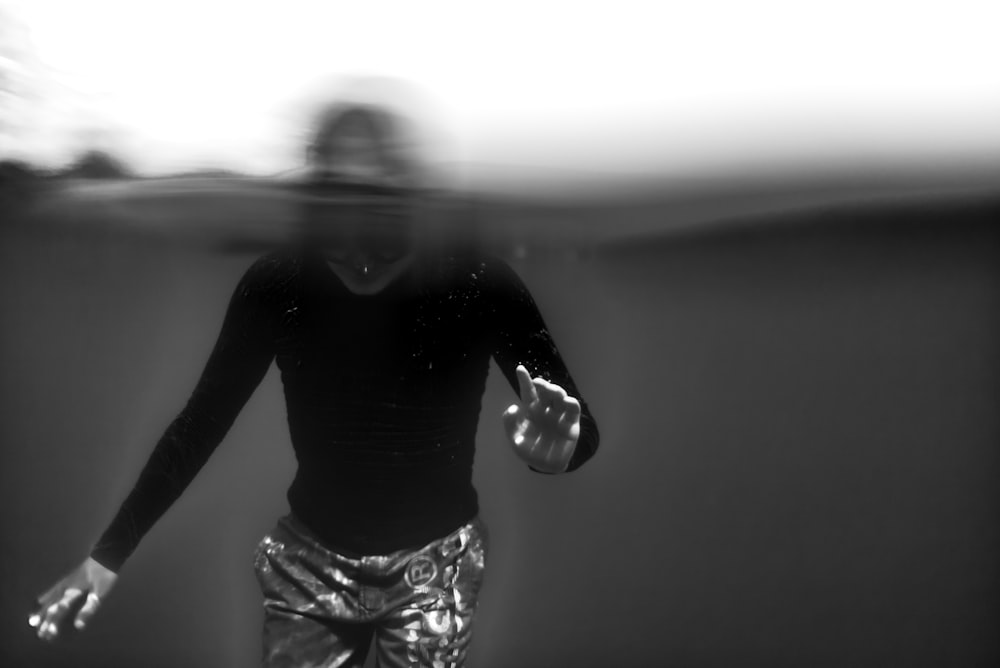 grayscale underwater photography of man dipped in water