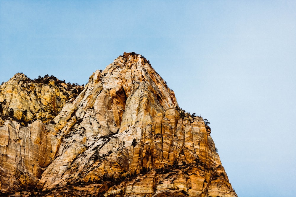 mountain cliff under blue and white sky