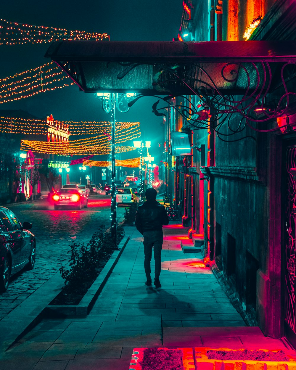 uomo che cammina lungo un marciapiede durante la notte
