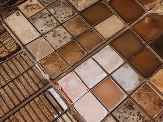 Numerous square salt evaporation ponds in various earthy colors with visible mineral deposits, separated by narrow pathways.