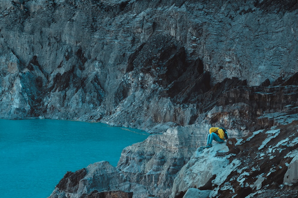 aerial photography of a man sitting in a mountain cliff