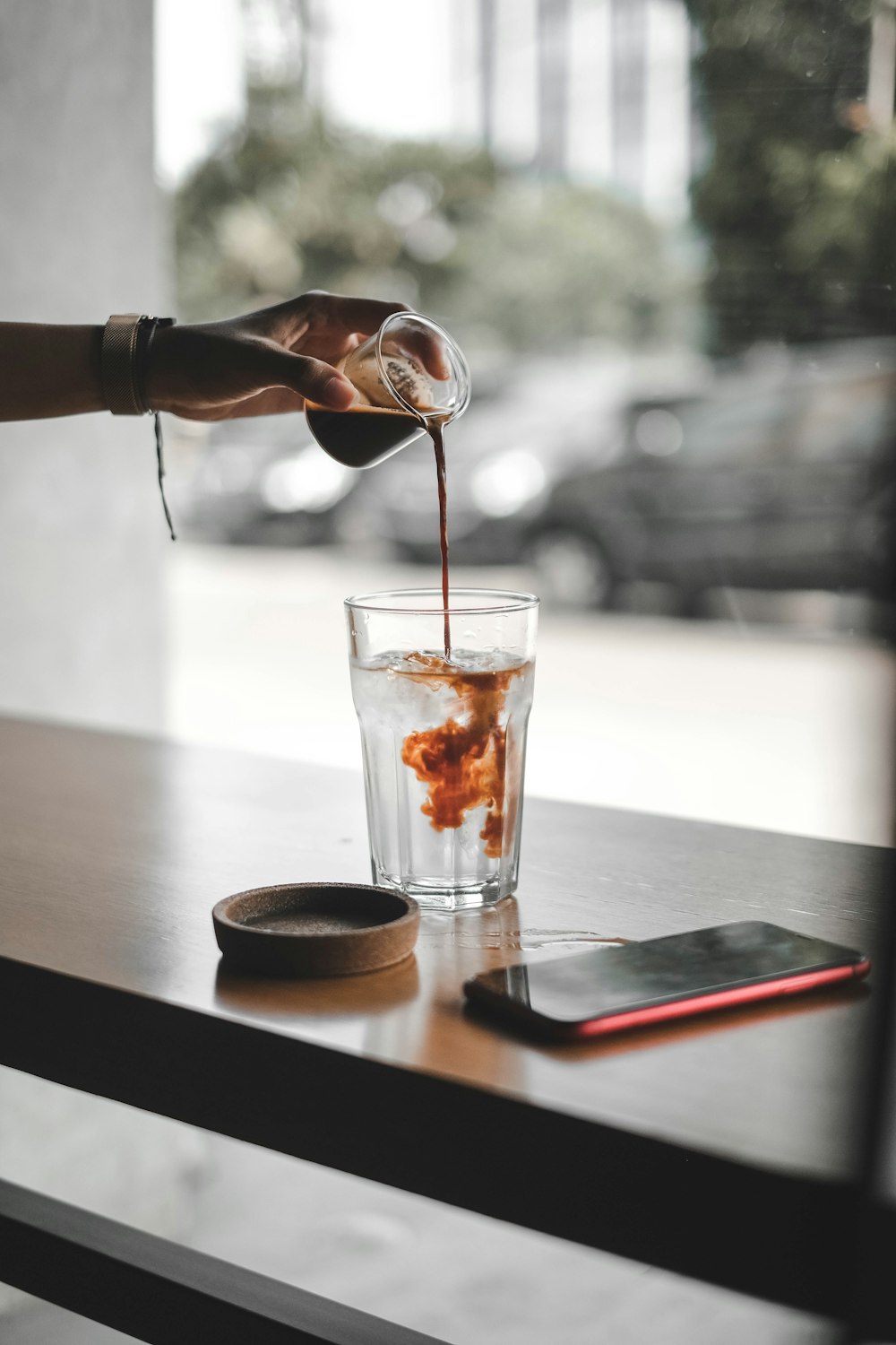 person pouring brown liquid on water