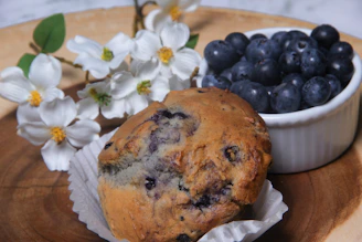 Close-up photo of a lavender muffin topped with edible lavender buds on a rustic wooden table.