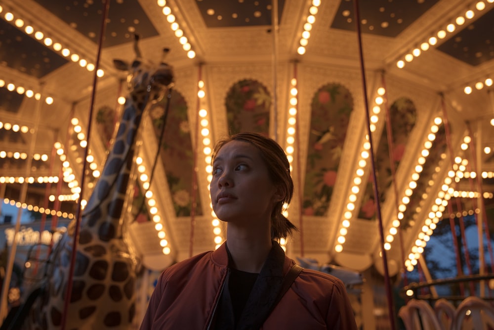 Mujer con chaqueta roja con cremallera en el parque de atracciones durante la noche