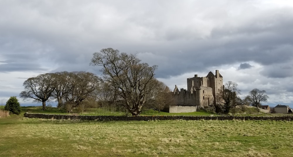 brown stone castle near green field under white and gray sky