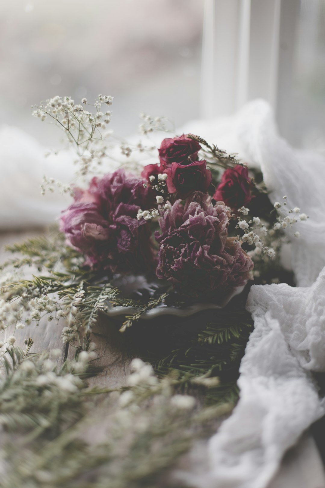 pink petaled flower bouquet on white textile