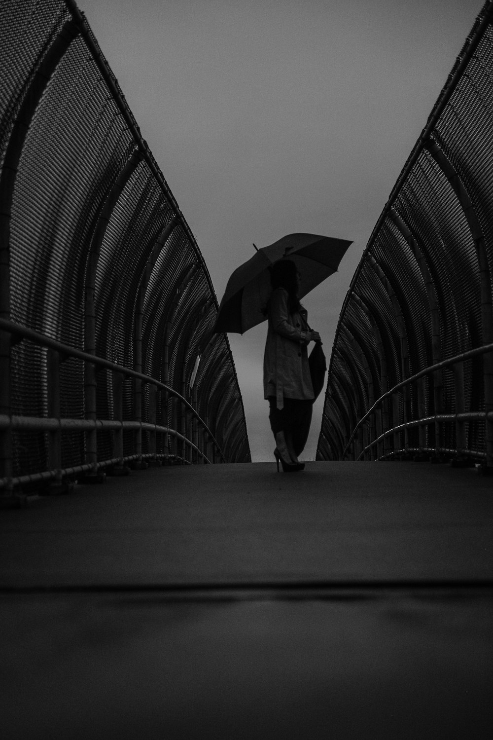 grayscale photography of woman using umbrella while standing on pathway