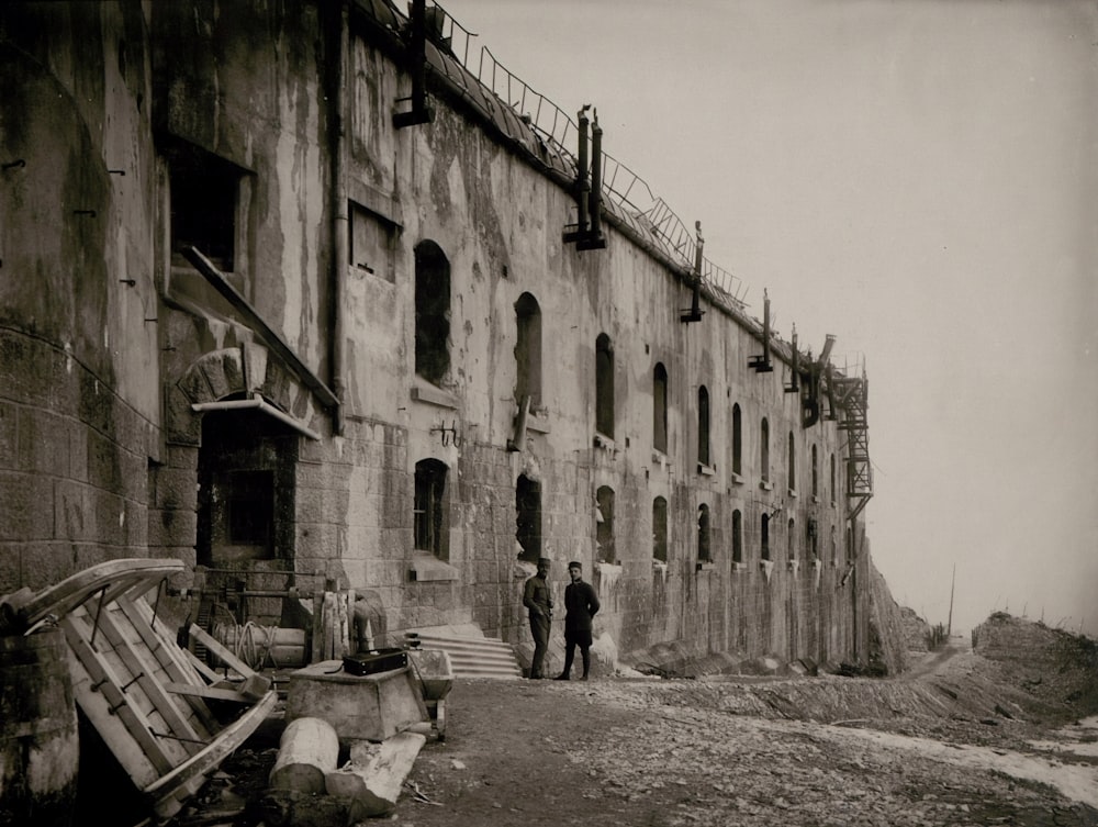 grayscale photography of two men standing outside a concrete building