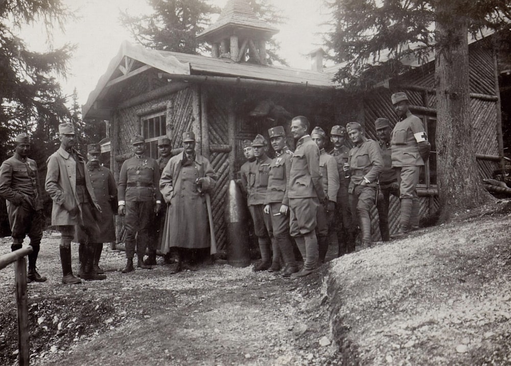 Photographie en niveaux de gris d’un soldat debout à côté d’une maison pendant la journée