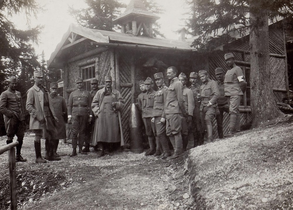 grayscale photography of soldier standing beside house during daytime