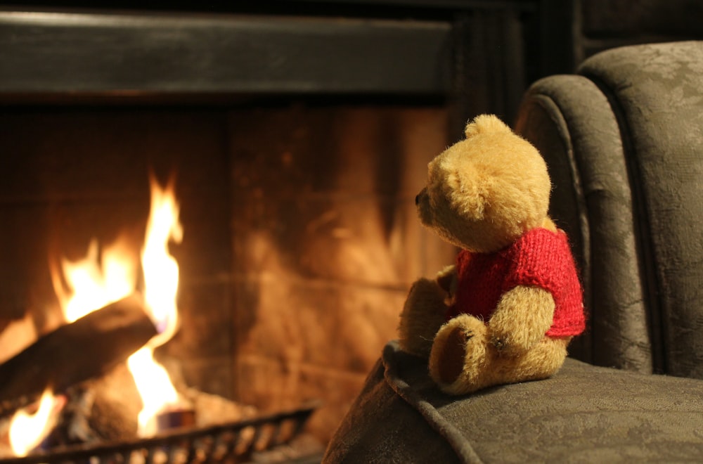 Winnie the Pooh plush toy placed on a sofa near a fireplace