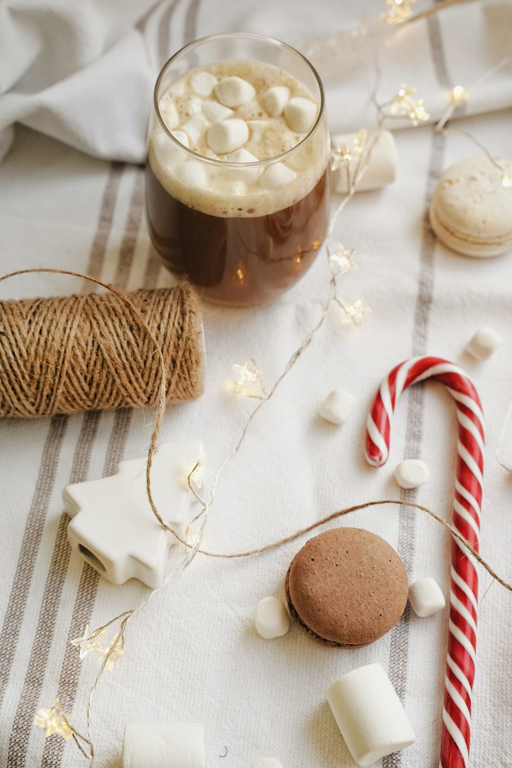 stringlights, drink with marshmallows on top, brown thread spool, macaroons, and candycane