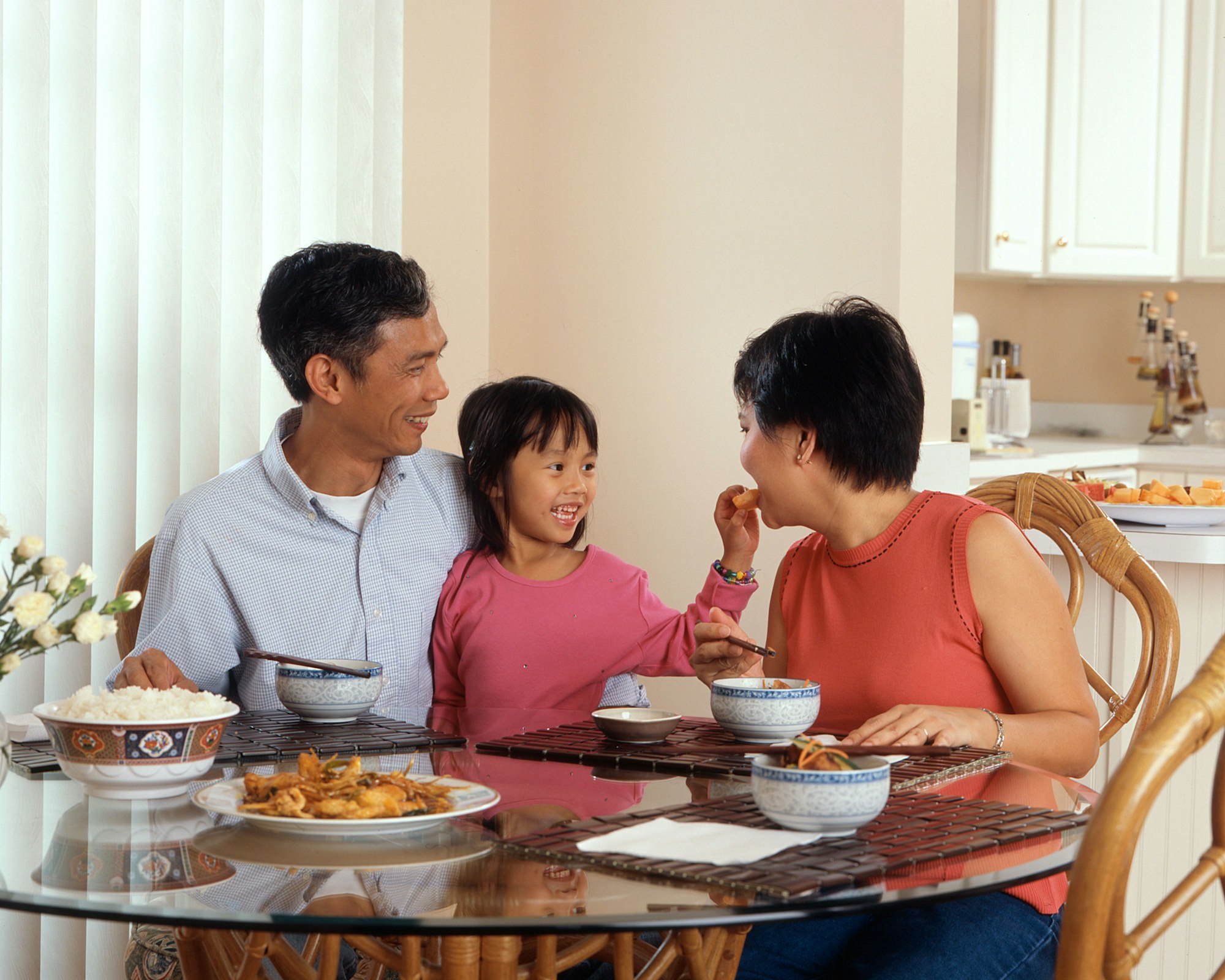 An Asian family eating together around the dining table.