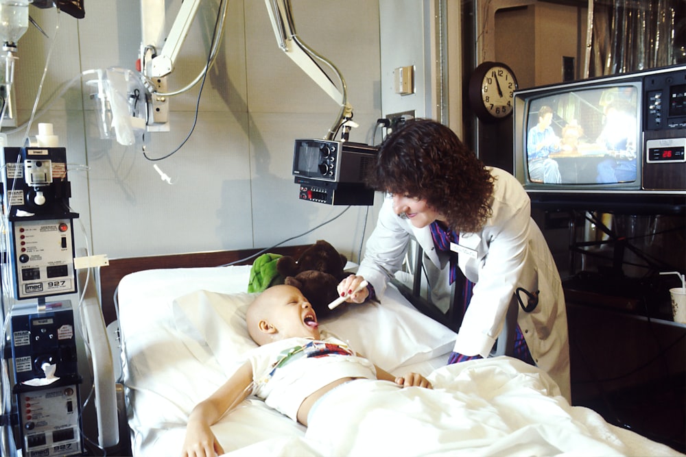 child lying on bed while doctor checking his mouth