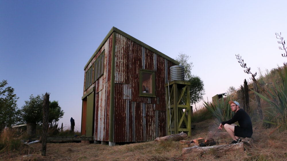 sitting man beside shed