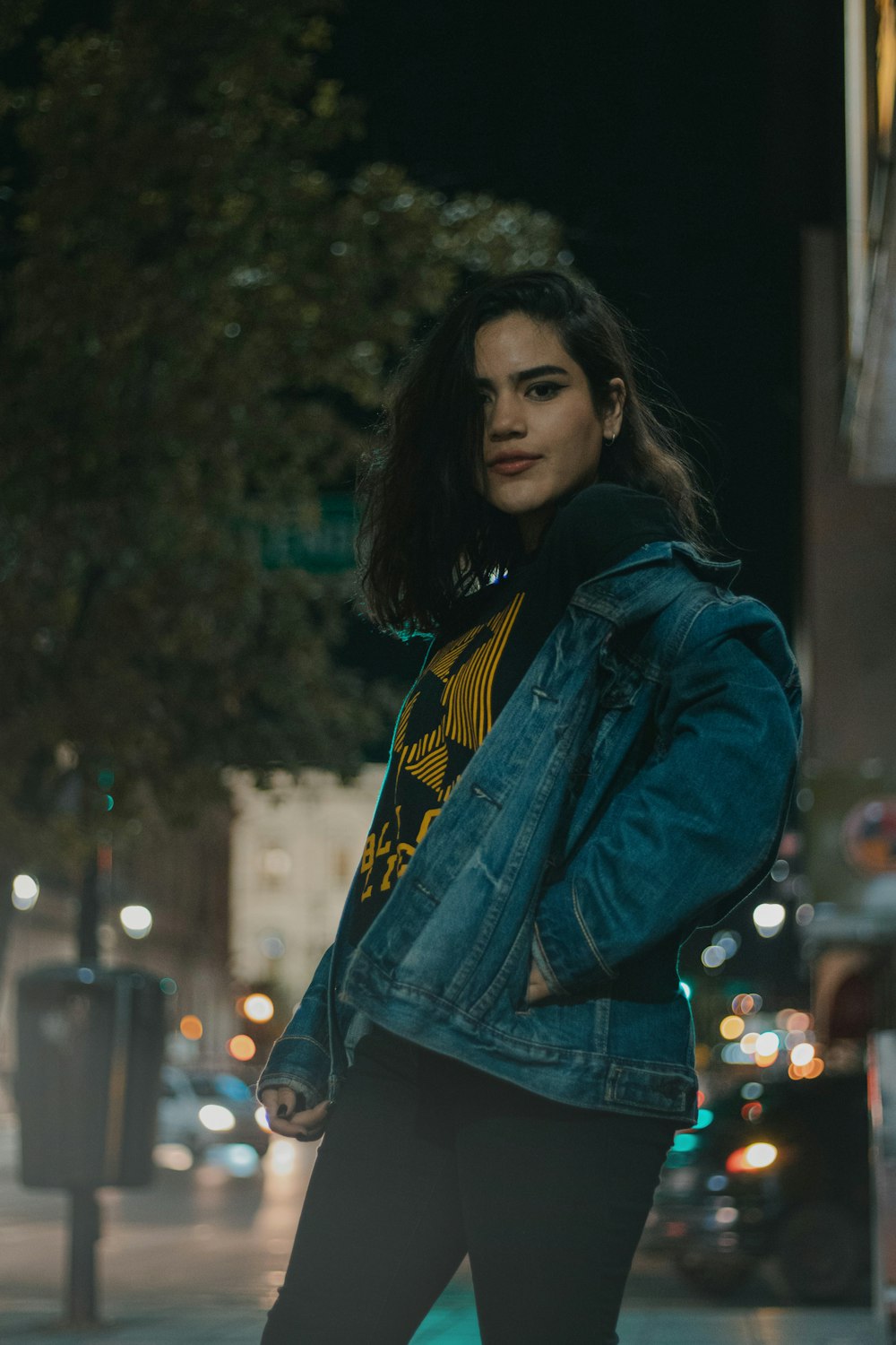 woman in blue denim jacket and black bottoms standing outdoors