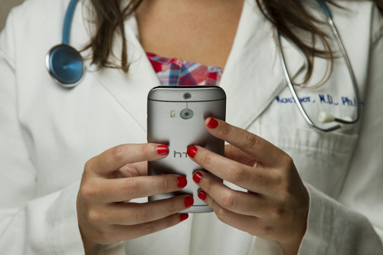 Close-up of a person examining a mole on their arm with a magnifying glass