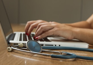 person sitting while using laptop computer and green stethoscope near