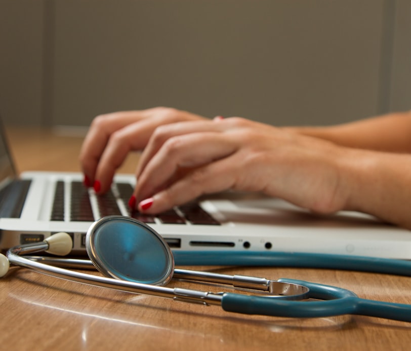 person sitting while using laptop computer and green stethoscope near