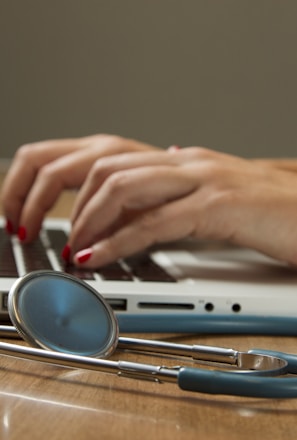 person sitting while using laptop computer and green stethoscope near