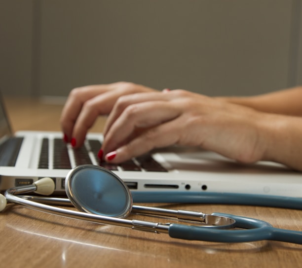 person sitting while using laptop computer and green stethoscope near