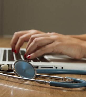 person sitting while using laptop computer and green stethoscope near