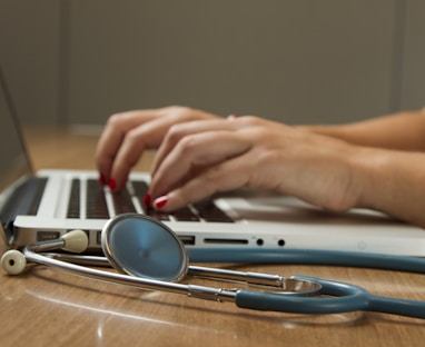 person sitting while using laptop computer and green stethoscope near