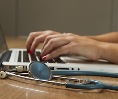 person sitting while using laptop computer and green stethoscope near