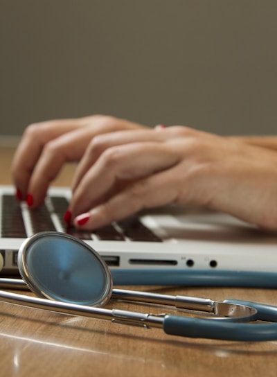 person sitting while using laptop computer and green stethoscope near