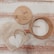 A bamboo lid with an illustration of a panda holding a small plant, a wooden container with EcoPanda labeling, and a mesh bag with a rustic white wooden heart attached are placed on a textured wooden surface.