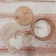 A bamboo lid with an illustration of a panda holding a small plant, a wooden container with EcoPanda labeling, and a mesh bag with a rustic white wooden heart attached are placed on a textured wooden surface.