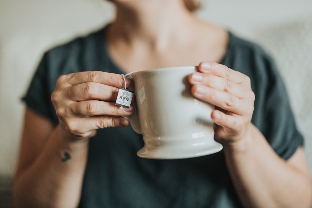 woman holding gray ceramic mug