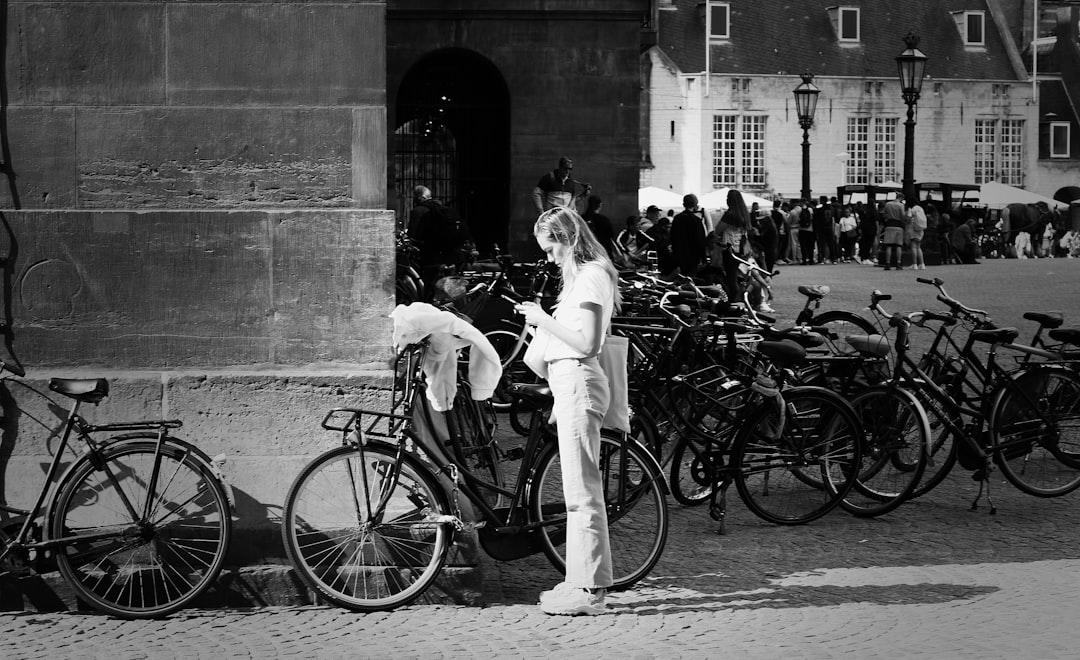 grayscale photography of woman standing beside step-through bike