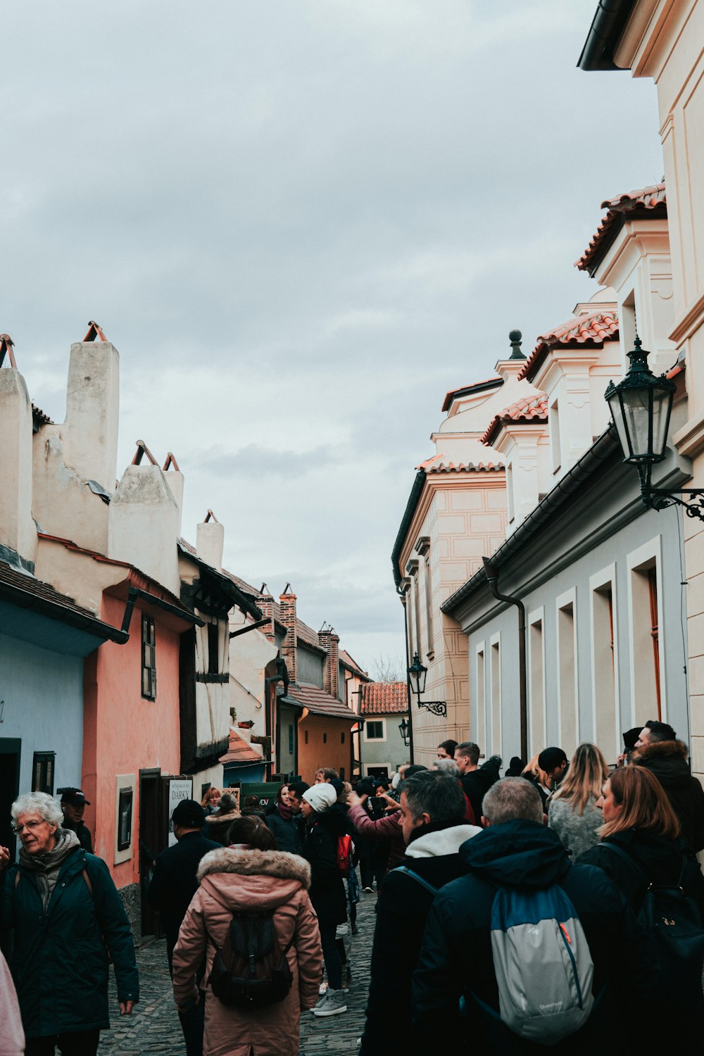 people waling between concrete buildings under calm sky