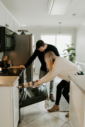 A friendly technician repairing a kitchen stove with tools in hand inside a bright, cozy home.