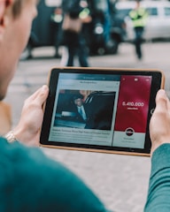 man wearing green long-sleeved shirt using iPad