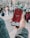 A hand holds a smartphone displaying a social media app with 118,000 subscribers on the screen. The image is set outdoors in a public plaza with multiple people blurred in the background.